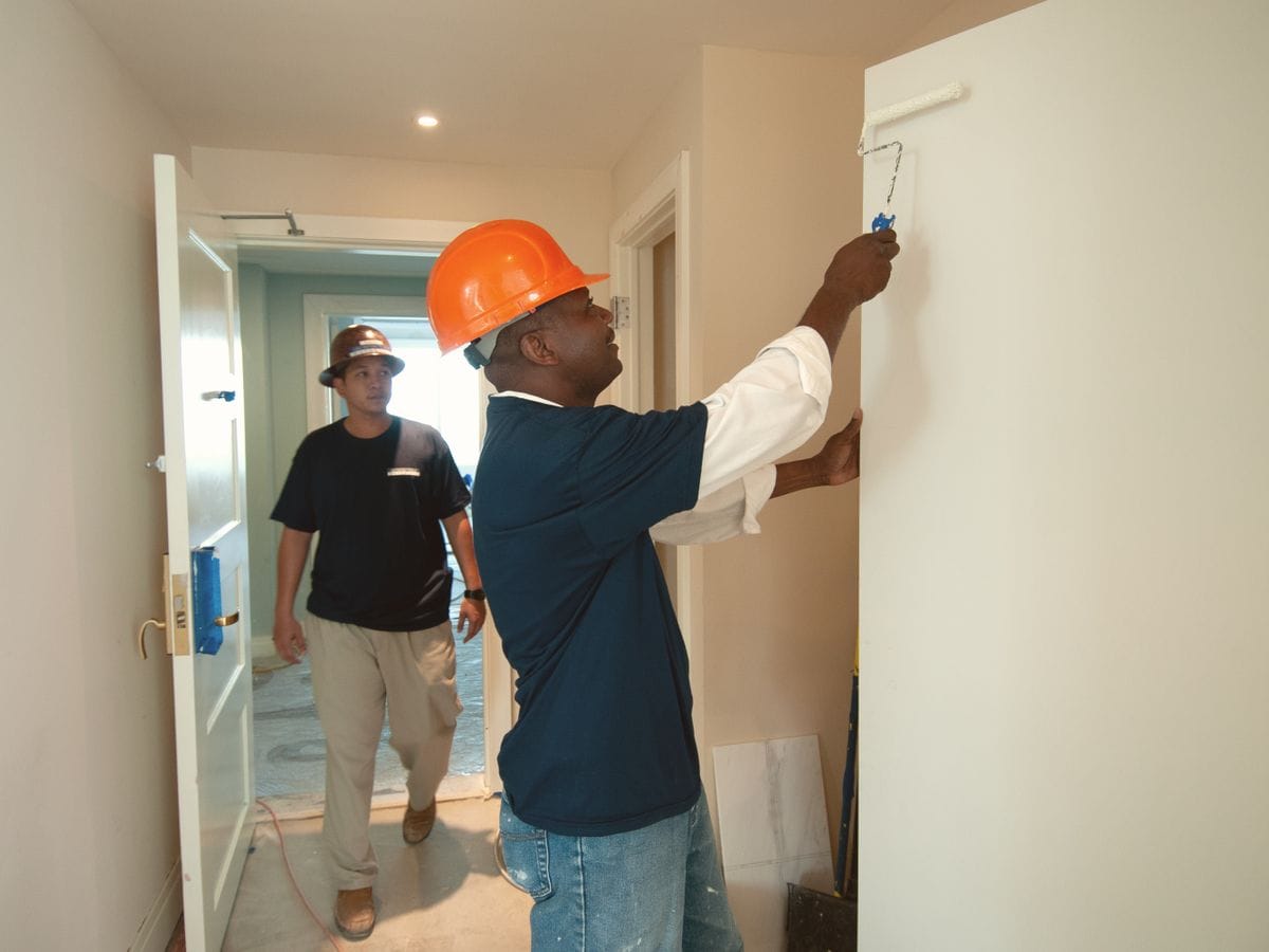 Two painters cutting in and rolling walls during an interior repaint