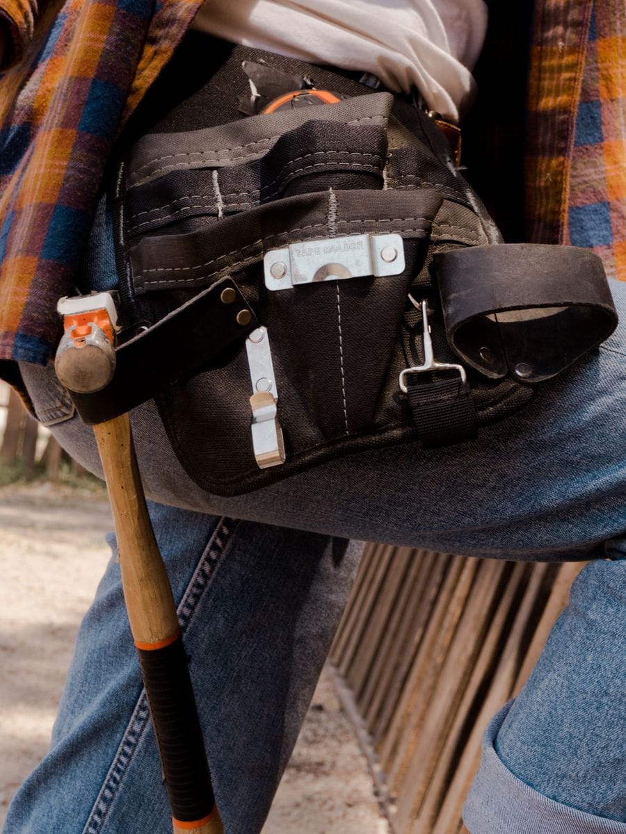 A tool belt loaded with a hammer, tape measure, and hand tools