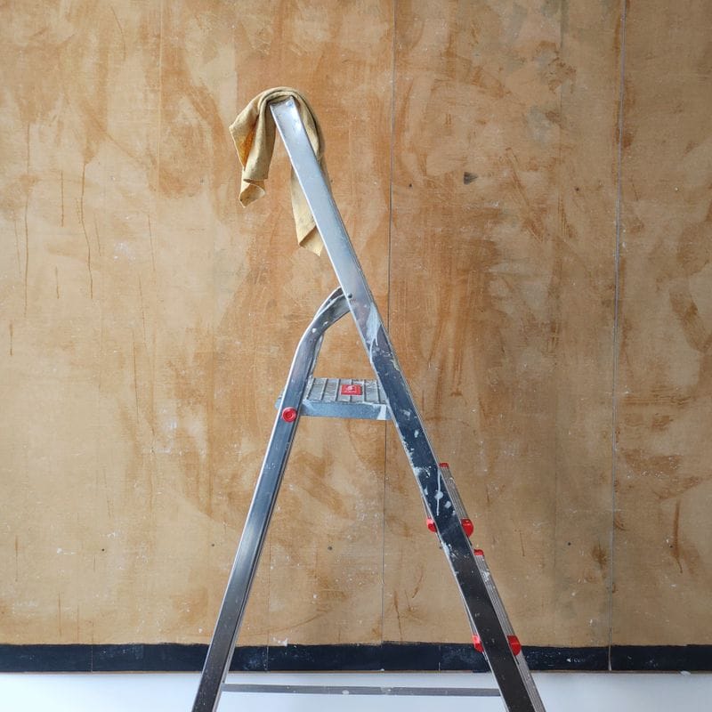 A stepladder standing against a stripped wall on a tidy job site