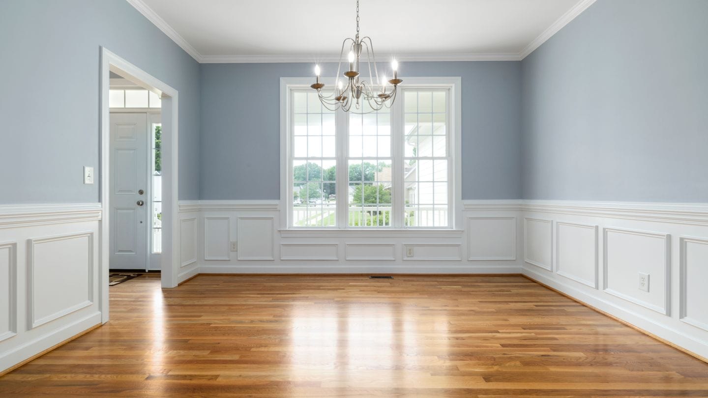 A finished wood floor running through a room with white wainscoting