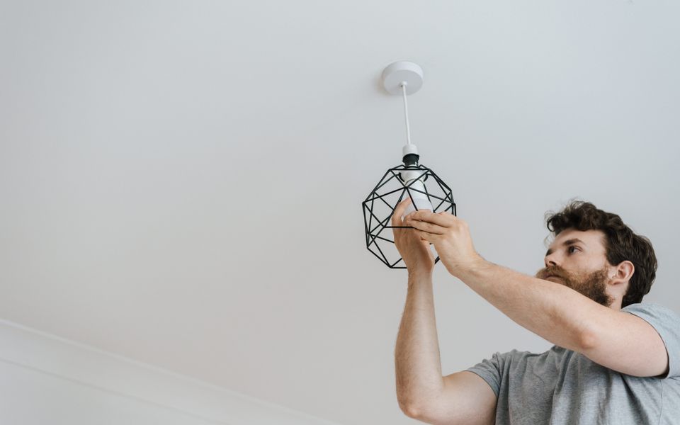 A pendant light being fitted to a ceiling