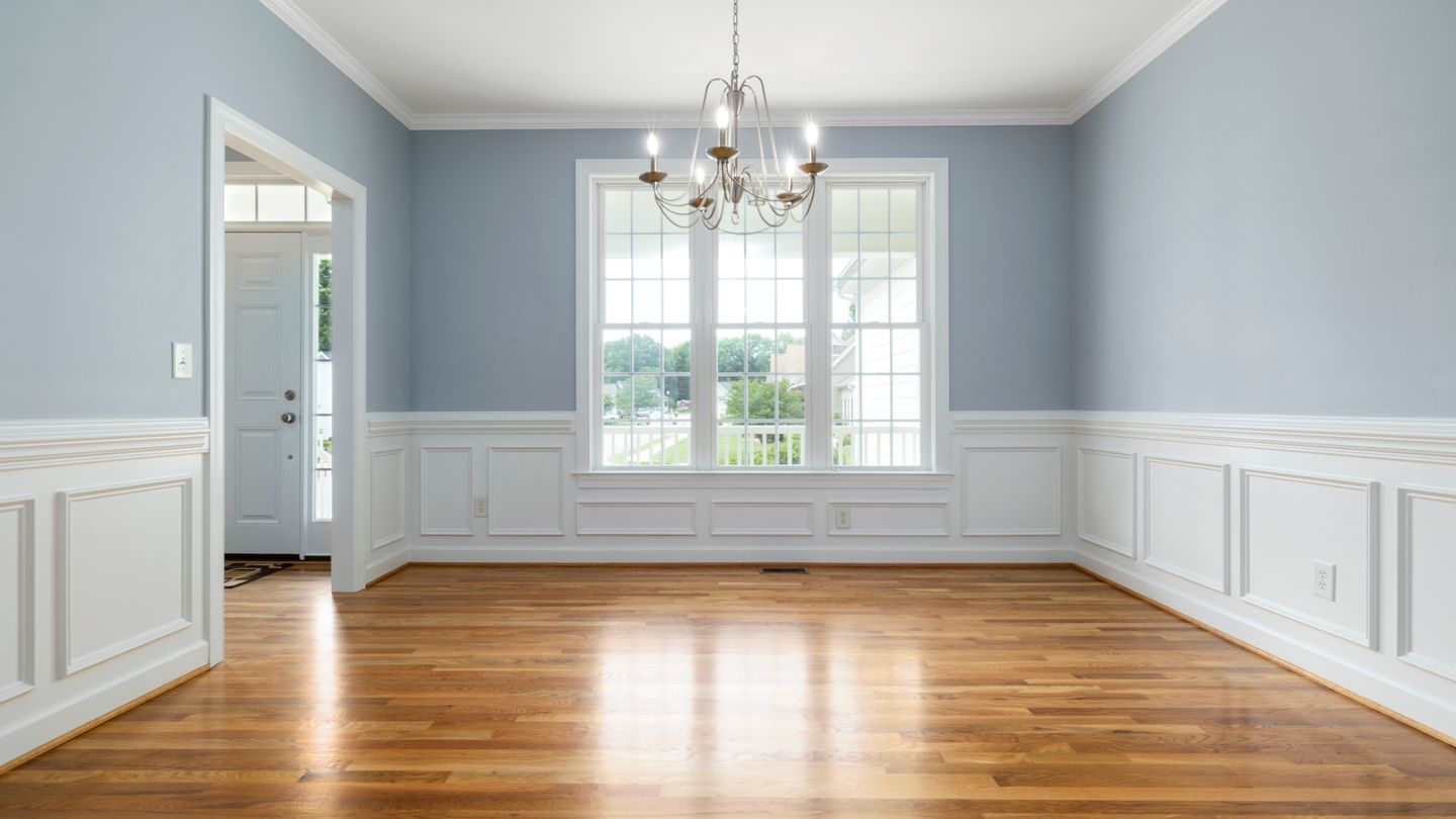 A finished wood floor running through a room with white wainscoting