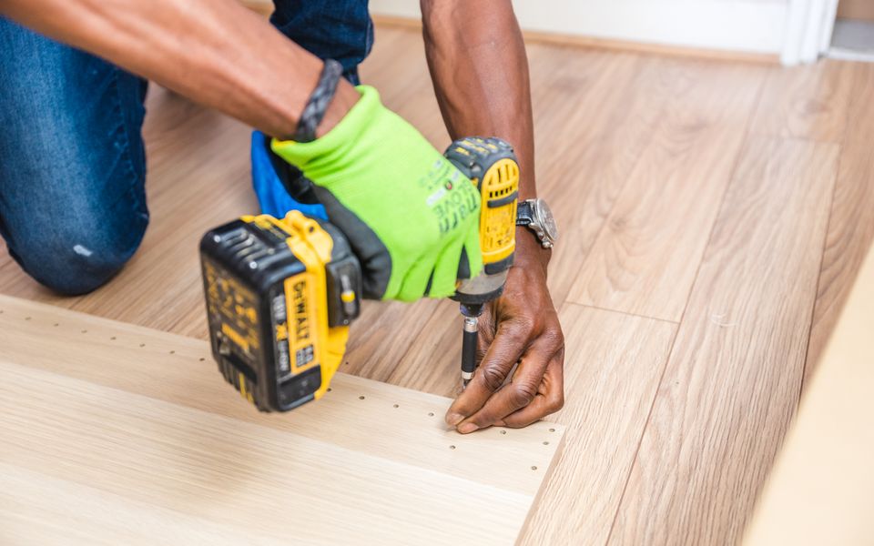 A cordless drill being used to fasten a board during a home repair